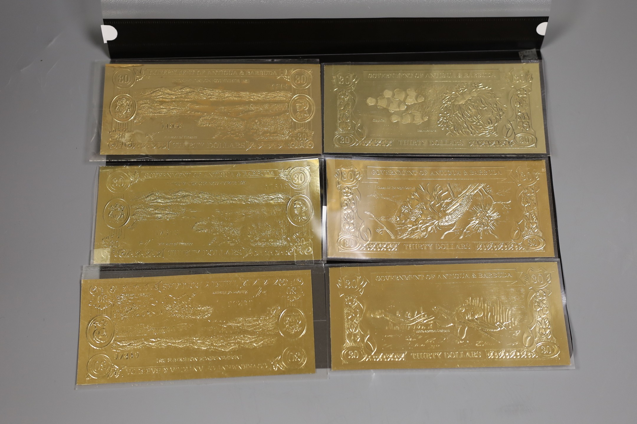 A collection of 30 Antigua & Barbuda gilt foil bank notes with folder , 75g weight